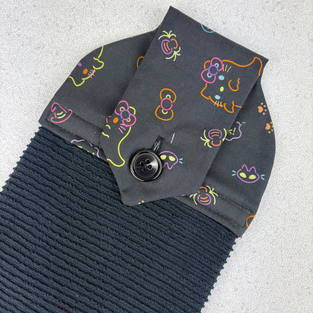 Dark gray fabric with colorful cat face patterns and a button on a light gray background, halloween, spooky