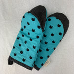Load image into Gallery viewer, A pair of oven mitts featuring a bright turquoise blue body with a black cat silhouette pattern, black-and-white patterned trim,
